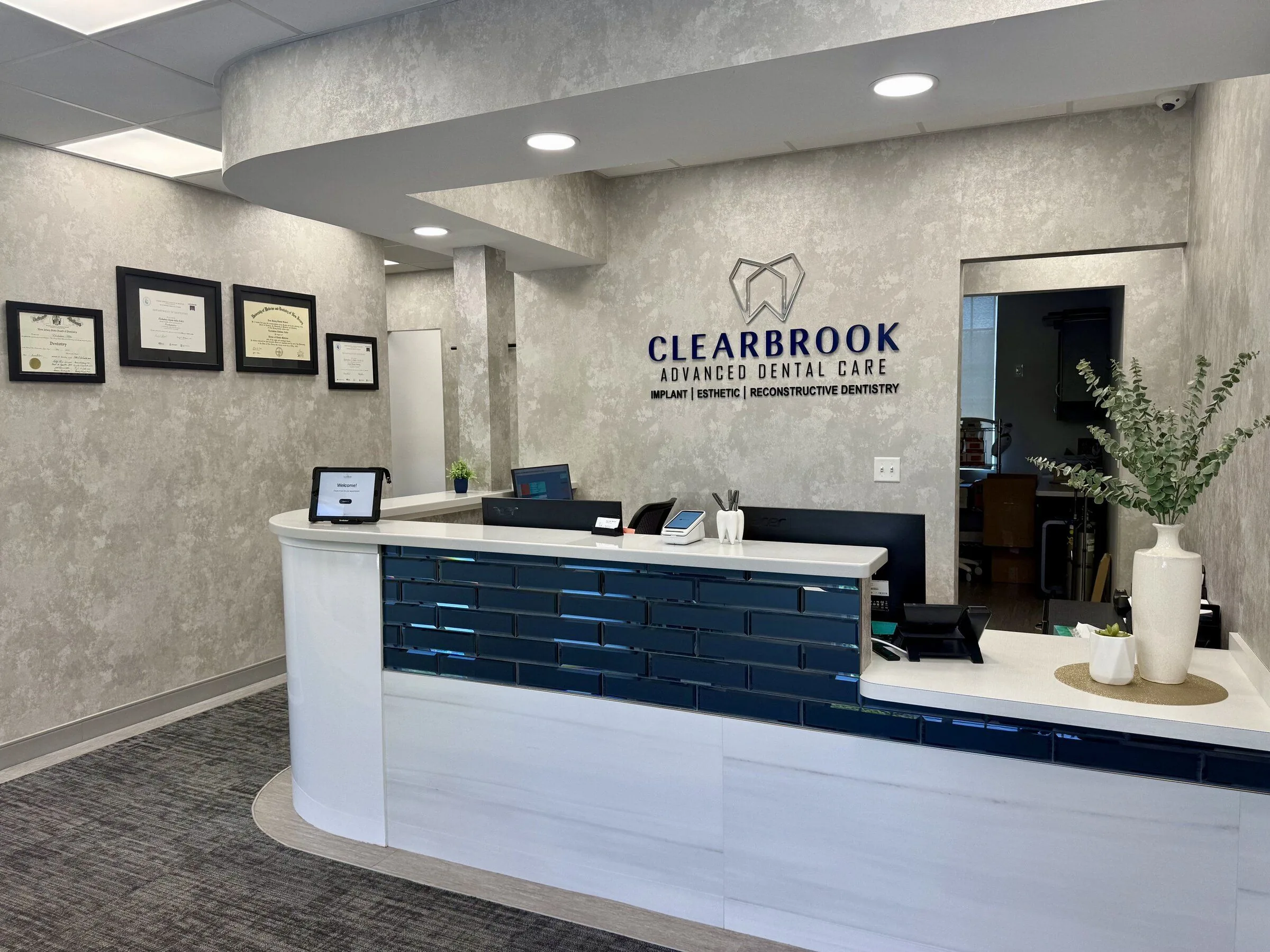 The reception desk and CLEARBROOK Advanced Dental Care logo wall sign in Cranbury, NJ